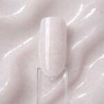 Polygel lichid Milky Pop N9 aplicat pe o mostră ovală pentru unghii, cu textura lucioasă a nuanței în fundal