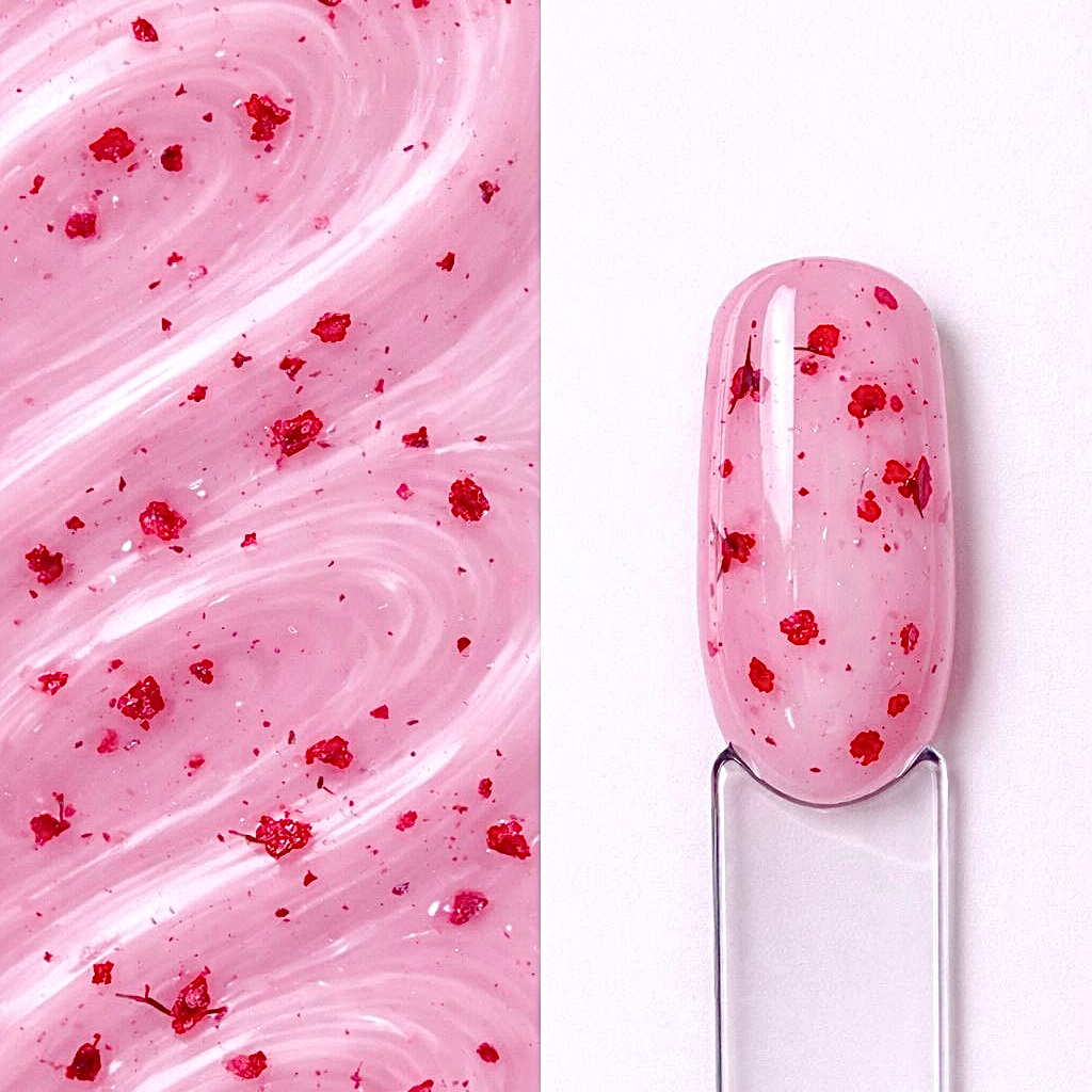 BuilderSculpt Flora MagentaGlass Builder gel Flora Magenta Glass N9 aplicat pe o mostră ovală pentru unghii, cu inserții florale vizibile și textura gelului în fundal